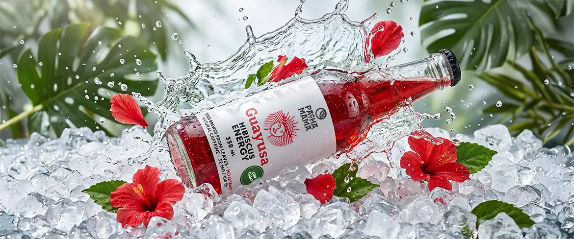 Guayusa Pachamama Cold Brew in een flesje op gemalen ijs met hibiscusbloemen.